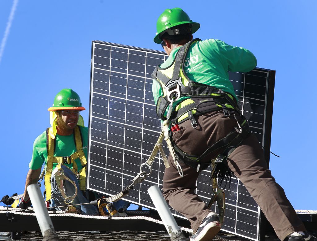 Workers install solar paneling.
