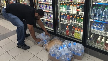 Keith Delahoussaye puts single bottles of water into a box after grabbing them from the cooler at a Beaumont convenience store early Thursday morning.    Photo/Scott Eslinger-KBMT